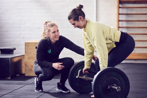 This is an Exercise Physiologist instructing a client on squatting technique